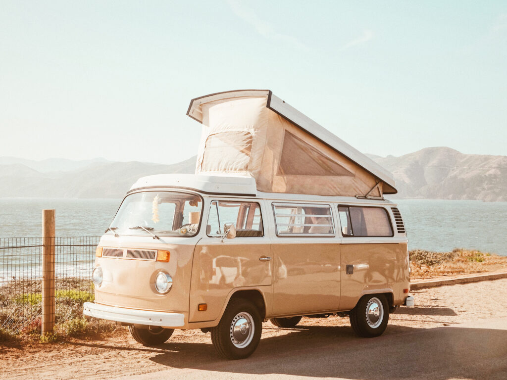 Classic pop-top campervan parked beside the sea with the roof raised